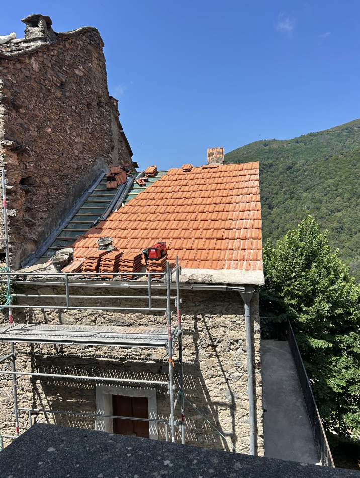 Toiture en tuiles neuves posée sur une maison de village en pierre